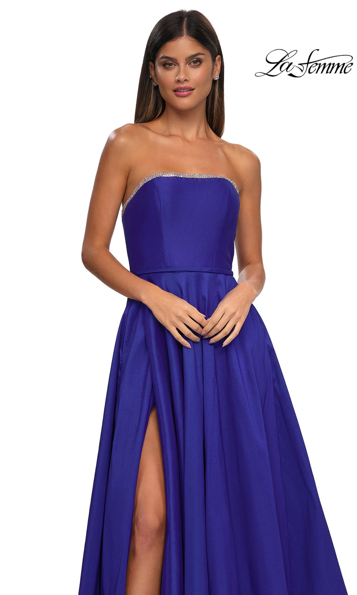 A woman models the La Femme 33063 strapless long A-line prom dress in royal blue with rhinestone beading and silver trim on the neckline, standing against a white background.